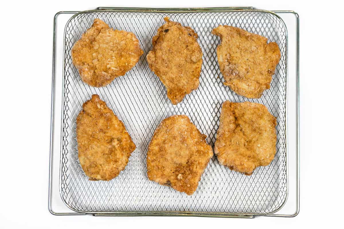 Six frozen chicken fillets in the air fryer basket.