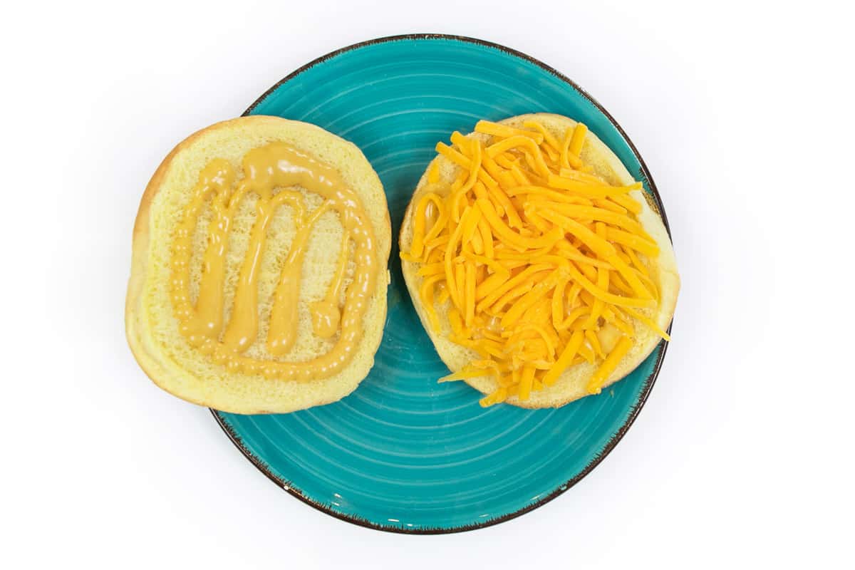 A sandwich bun with Chick-fil-A sauce and cheddar cheese on a plate.