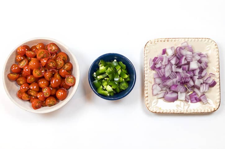 One pint of cherry tomatoes cut in halves, one jalapeño pepper chopped with a few seeds too, and one red onion that is chopped.