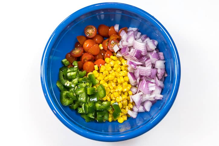 Corn, tomatoes, jalapeño peppers, and the red onions in a bowl.