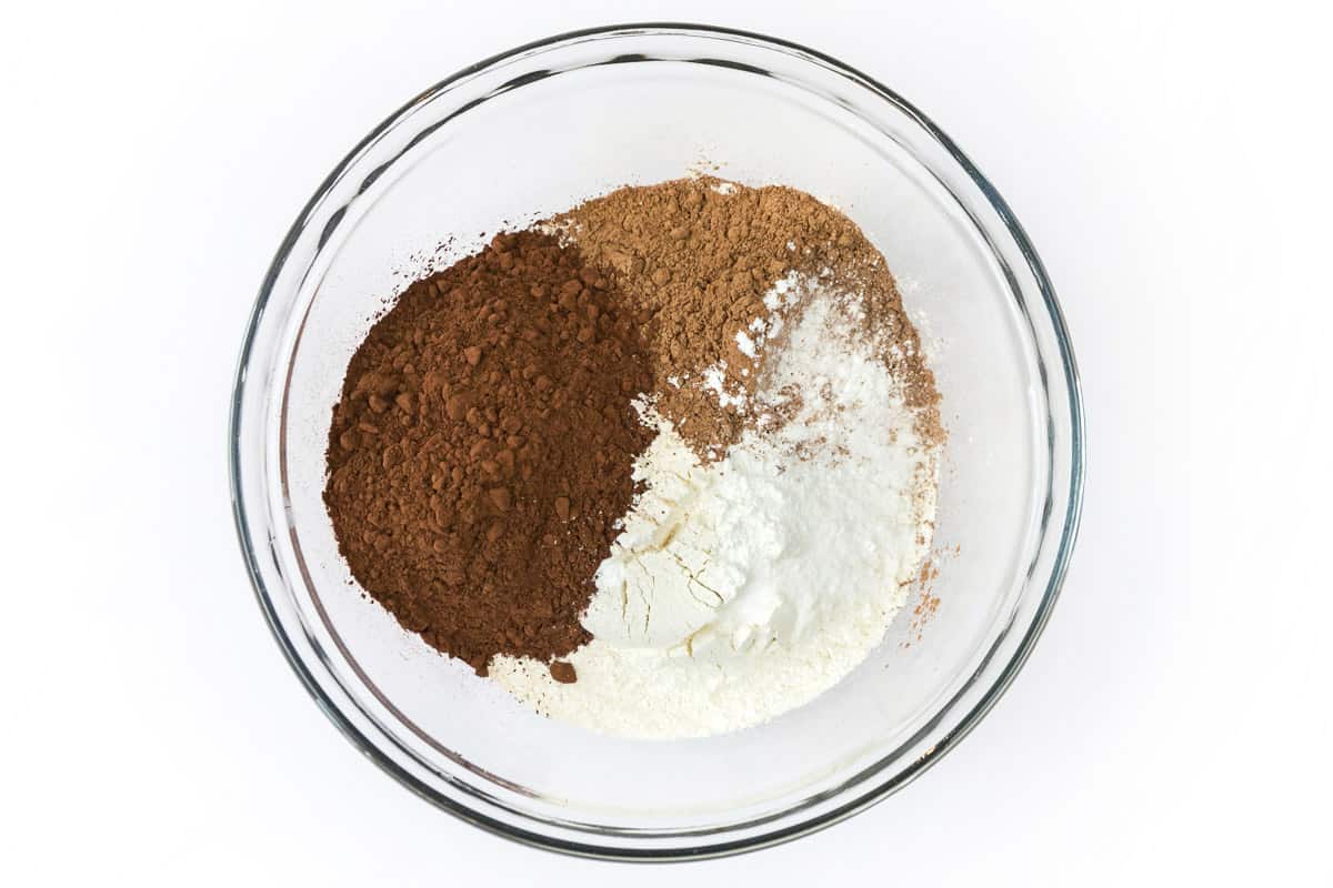 Flour, dark cocoa powder, unsweetened cocoa powder, baking soda, baking powder, and salt are added to a bowl.