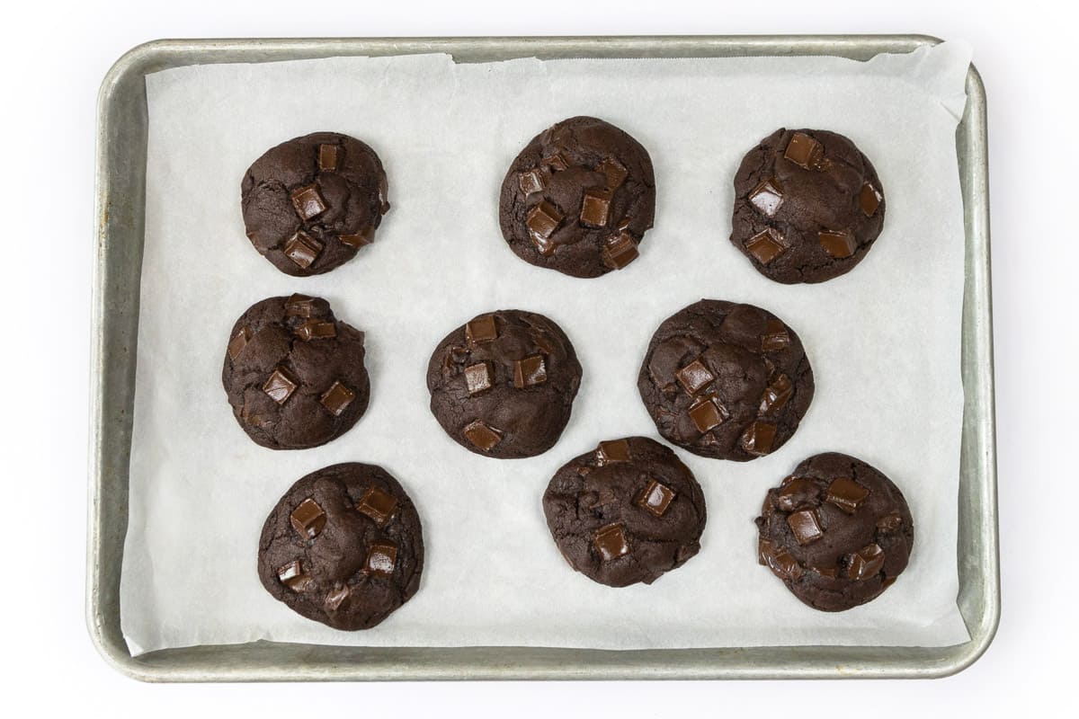 Dark chocolate cookies on a cookie sheet after baking in the oven.