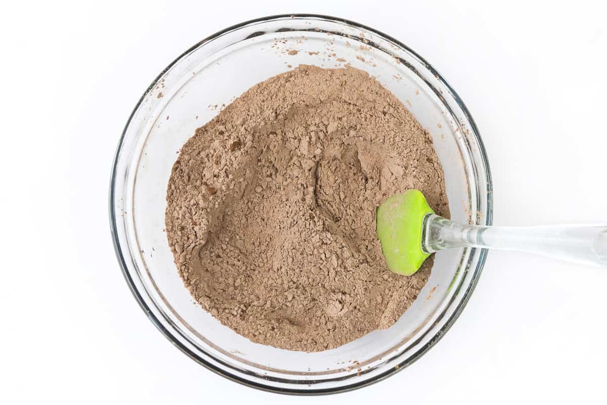 Flour, dark cocoa powder, unsweetened cocoa powder, baking soda, baking powder, and salt are mixed in a bowl.