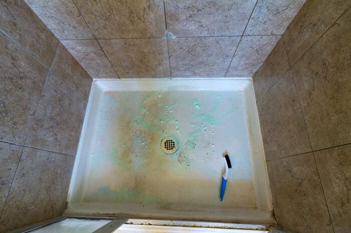 scrub brush on dirty shower pan