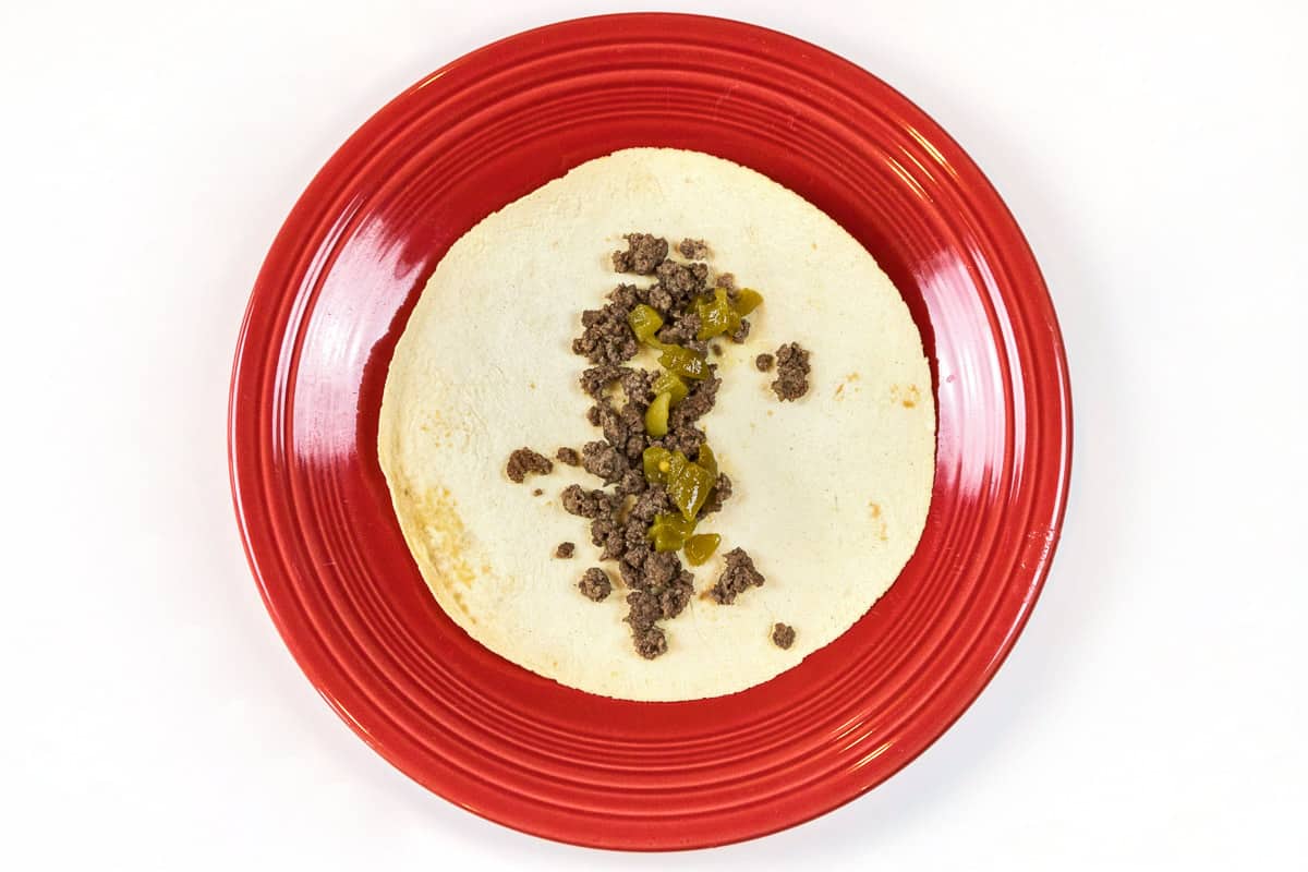 Put ground beef and diced green chiles across the middle of the tortilla.