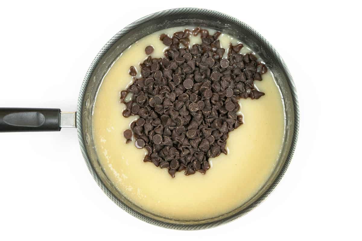 Semi-sweet chocolate chips are added to the butter, sugar, and evaporated milk in the saucepan.