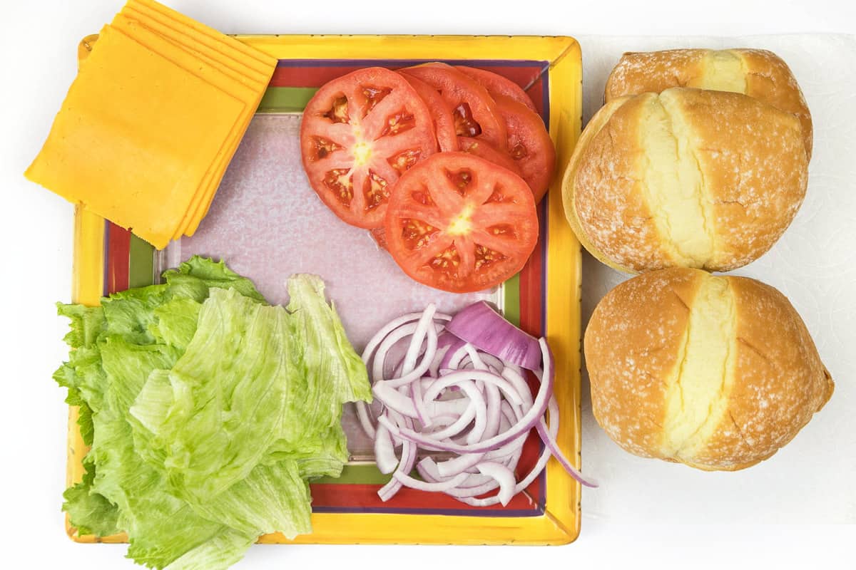 Cheddar cheese, sliced tomato, sliced red onions, lettuce, and hamburger buns.