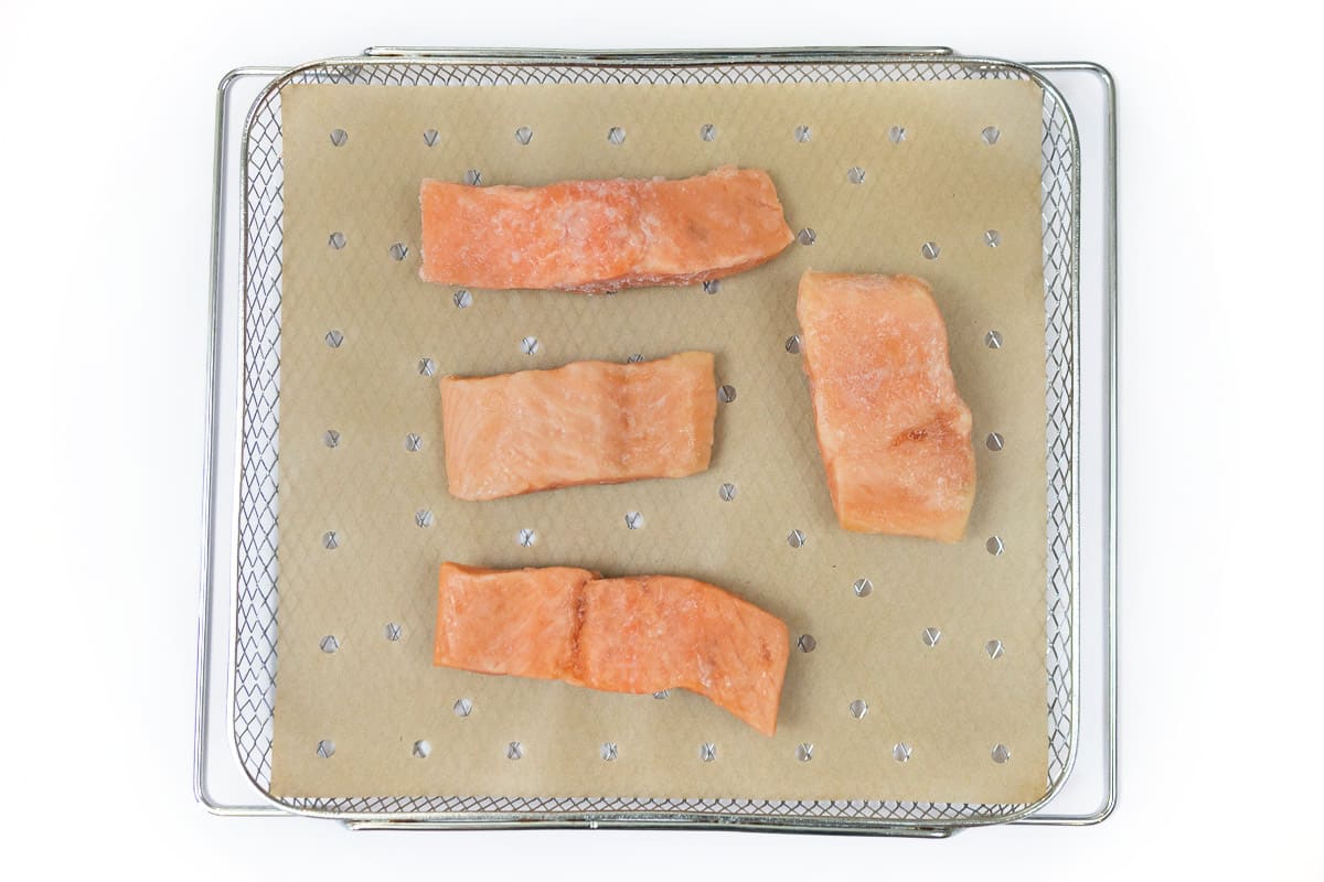 Salmon fillets are placed in a single layer on parchment paper.