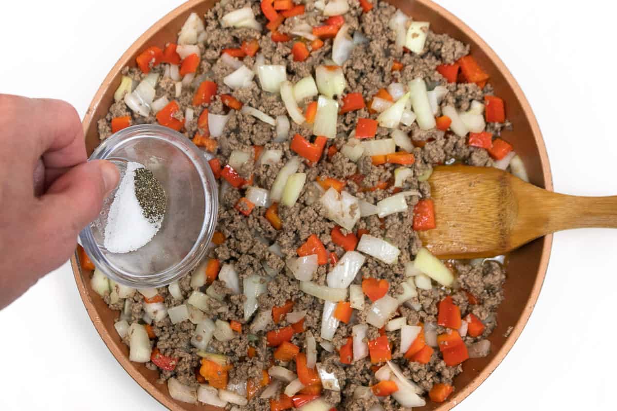 Salt and pepper are added to the ground beef mixture.