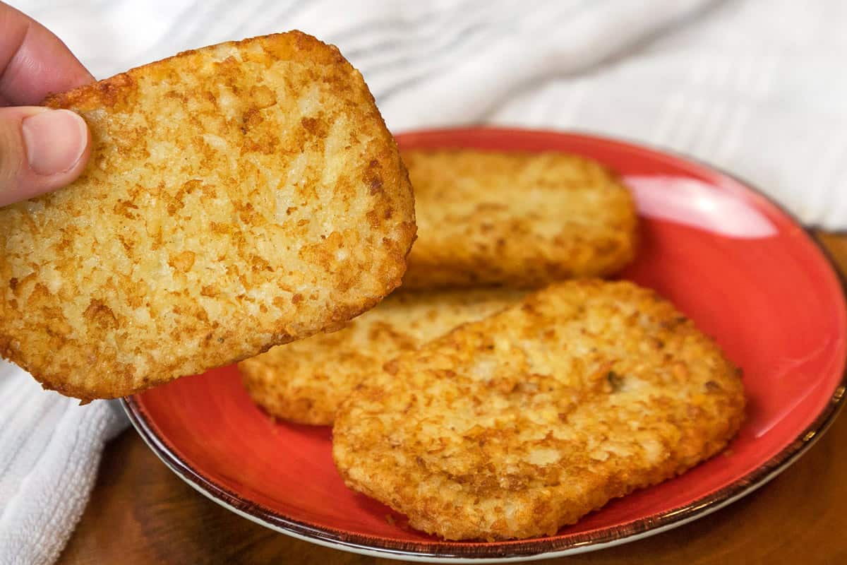 Four hash browns on a plate after cooking in the air fryer for twenty-two minutes.