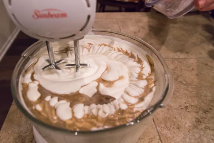 Keep the mixer on low speed and slowly add two teaspoons of vanilla extract to the condensed milk and whipping cream.