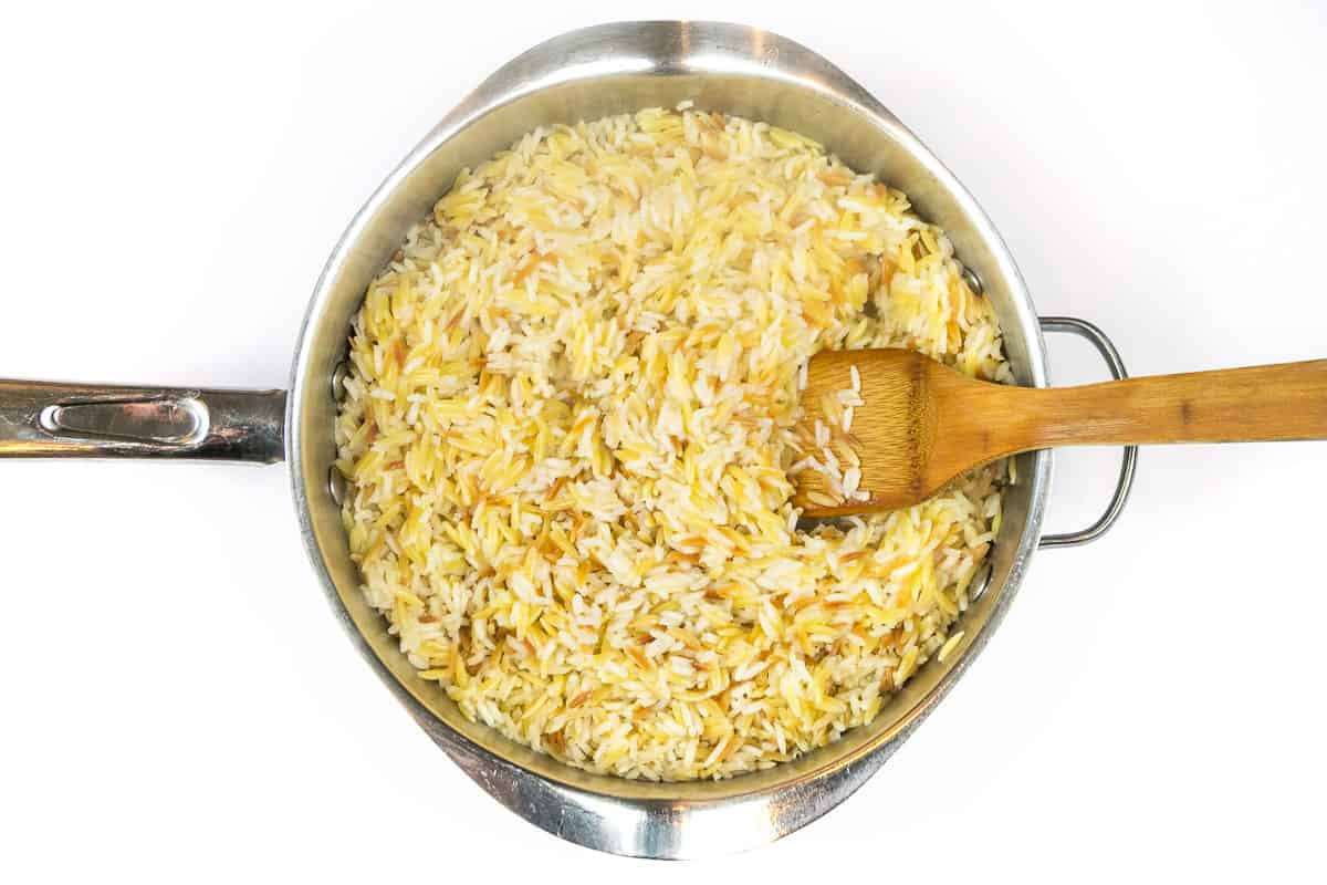 Cook the chicken broth, long-grain rice, and orzo pasta in a frying pan for fifteen minutes.