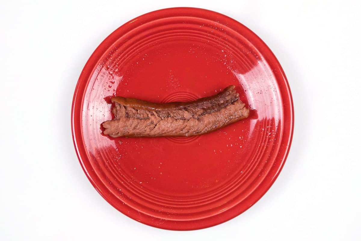 Exploded hot dog on a red plate.