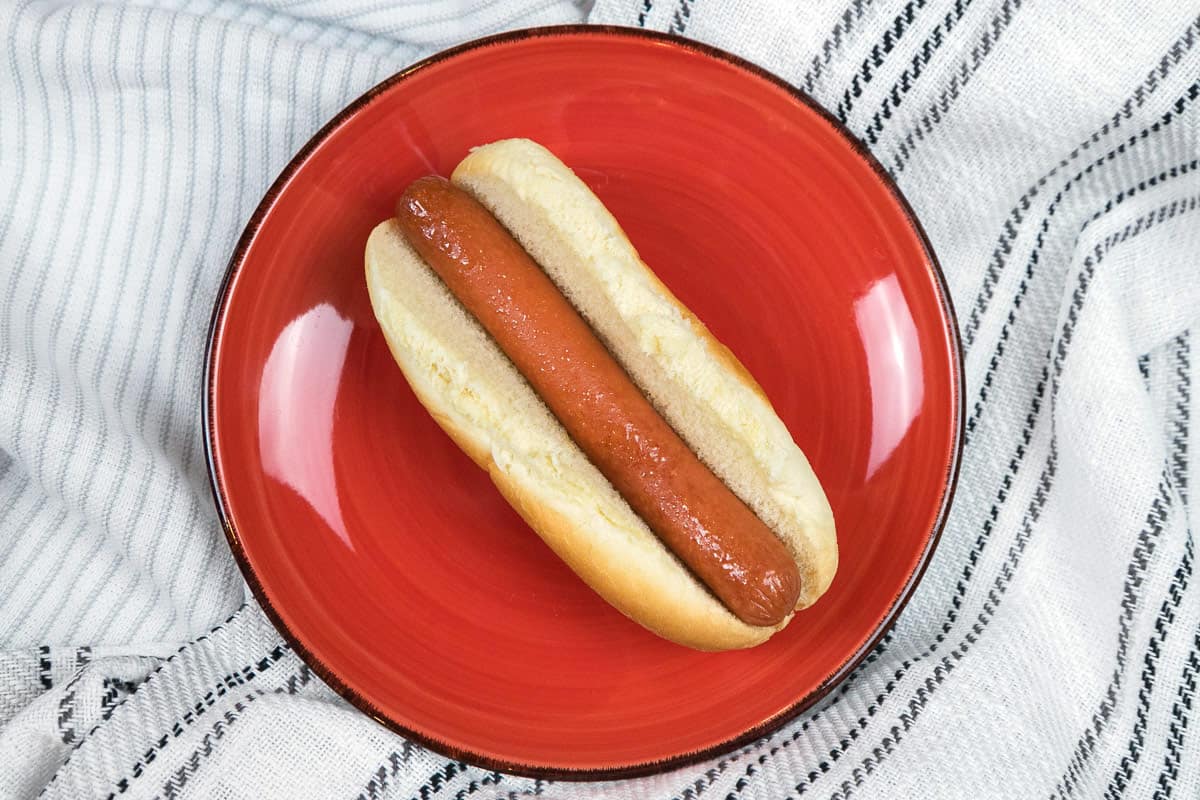 Microwaved hot dog and bun on a plate.