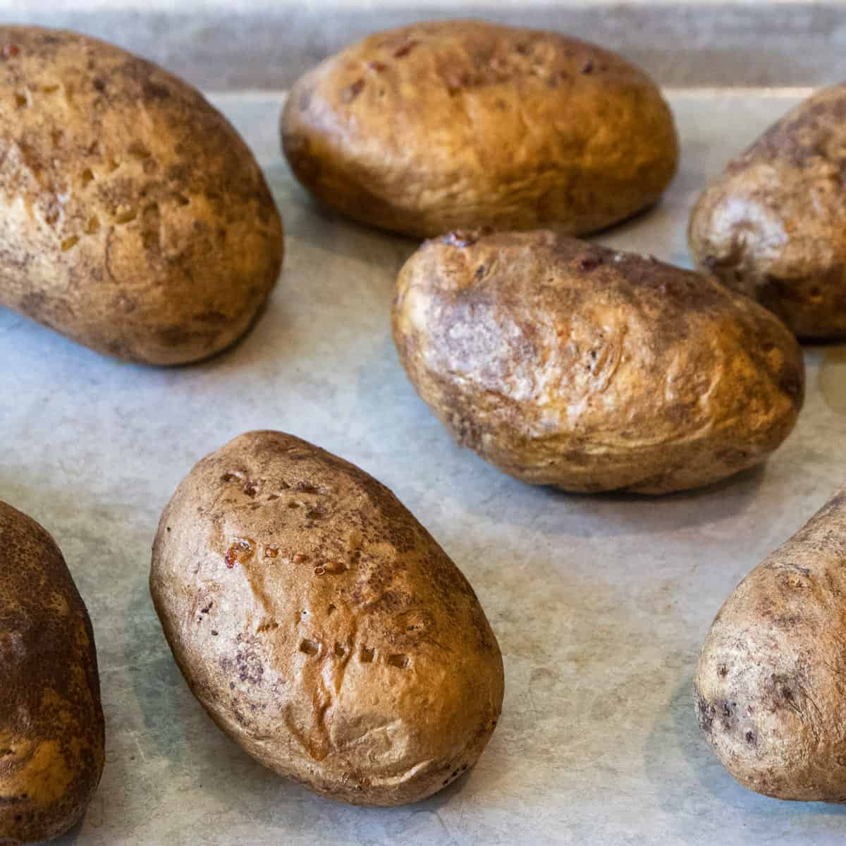 Rub olive oil on the potatoes, then bake the potatoes in the oven at four hundred degrees Fahrenheit for one hour.