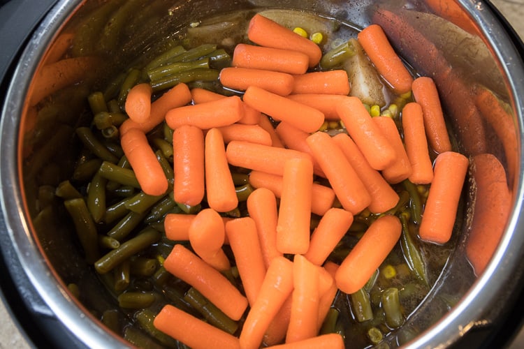 After seventy minutes, add the raw baby carrots, corn, and green beans.