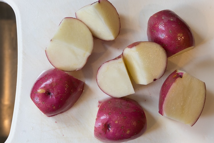 Three red potatoes not peeled and cut into fourths.
