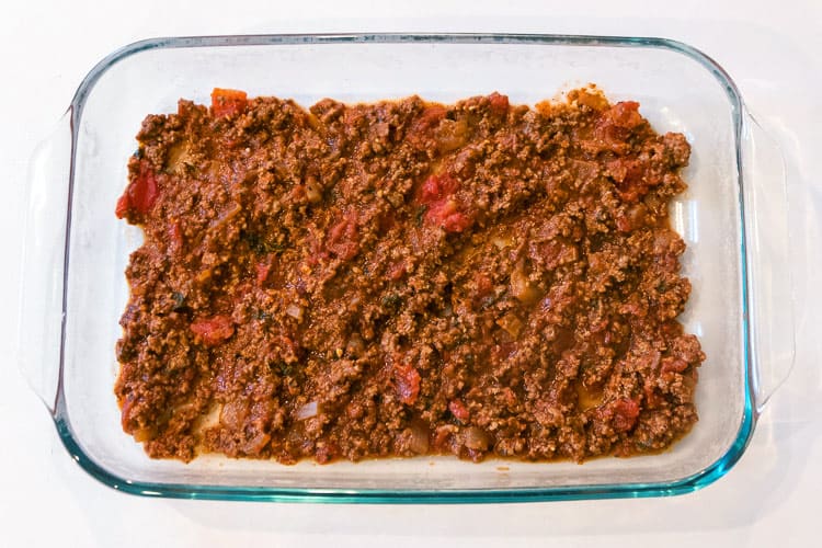 The first layer is ground beef in the nine by thirteen inch baking dish.