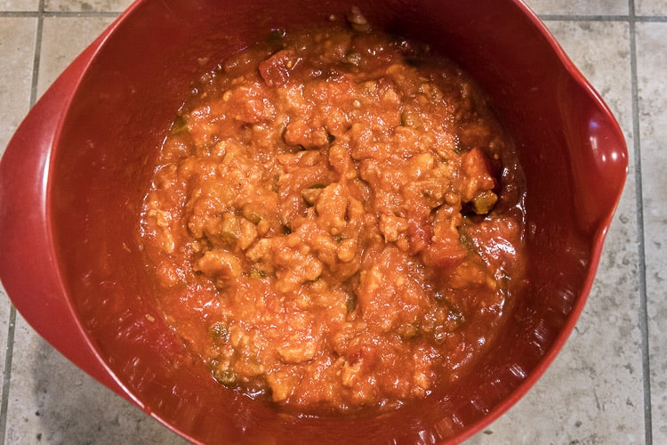 Medium-hot thick and chunky salsa mixed with refried beans in a bowl.