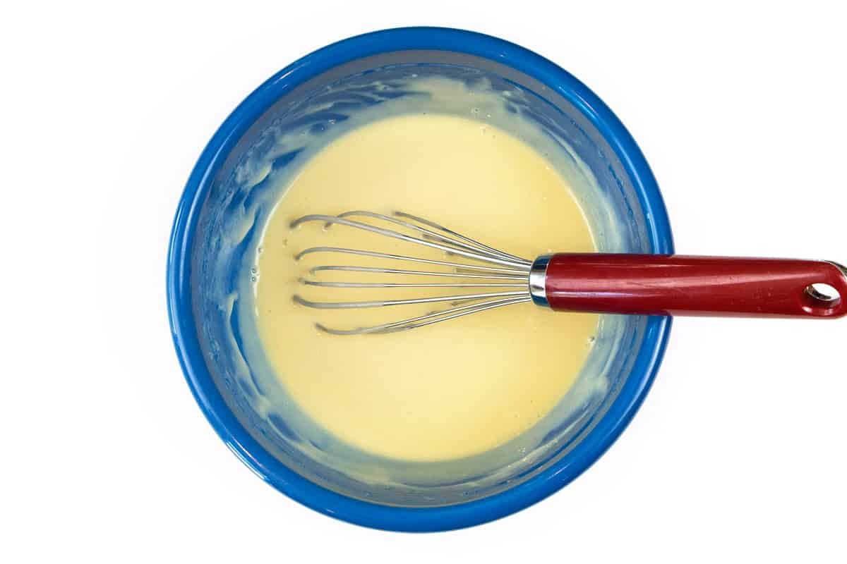 Lemon juice, egg yolks, and sweetened condensed milk are mixed in a bowl.
