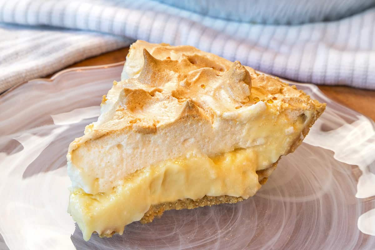 A slice of lemon meringue pie with condensed milk on a plate.