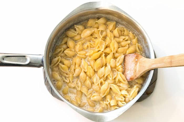 Macaroni shells are cooked on the stove on medium-high heat for nine minutes.