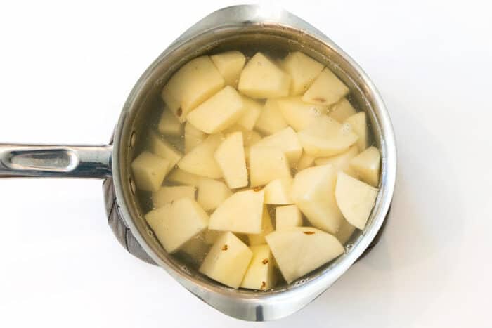 Cut up potatoes in a pot of water.
