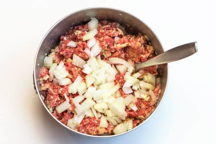 Mix diced yellow onions with the ground beef mixture.