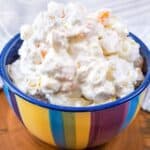 Fruit salad with cool whip recipe in a colorful bowl close up.