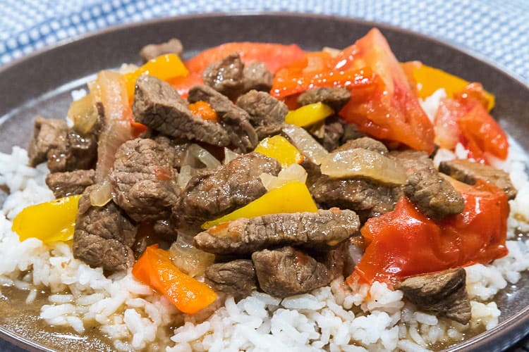Close up of pepper steak with tomatoes on a bed of white rice.
