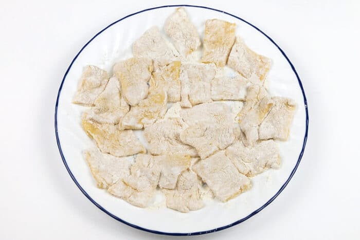 Pierogi dough squares on a plate.