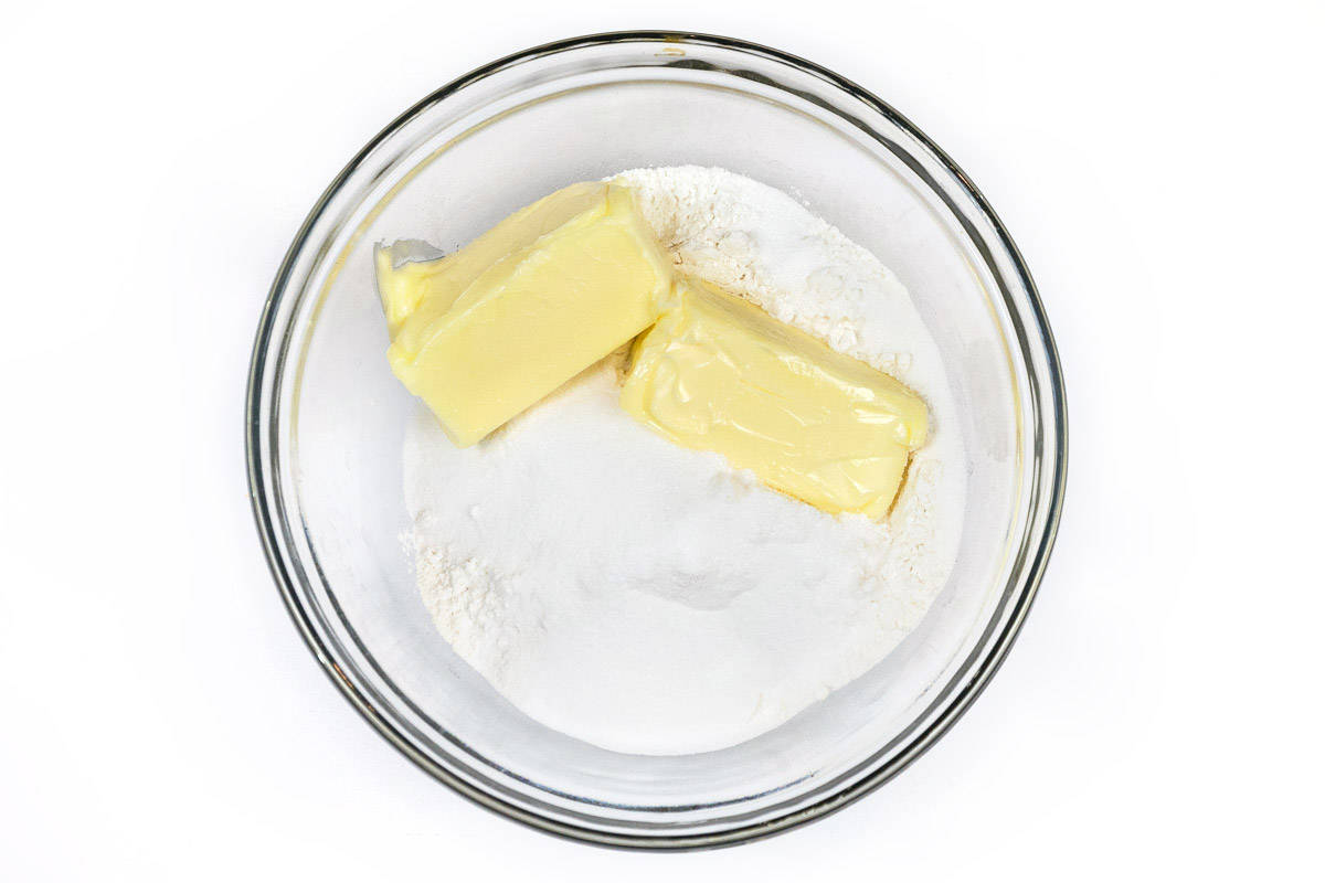 Two cups of all-purpose flour, four tablespoons of granulated sugar, and one cup of the softened butter in a bowl.