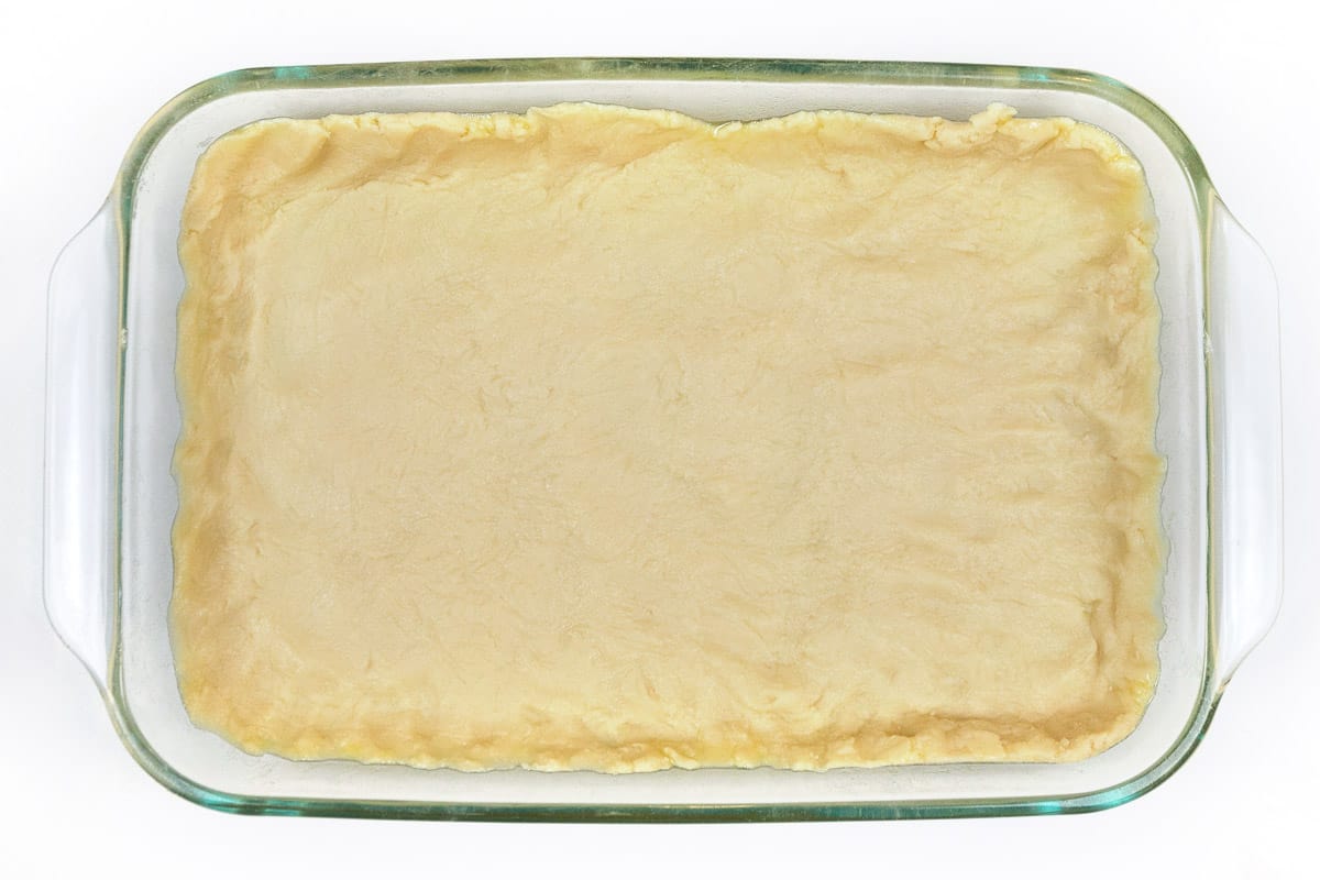 An unbaked homemade pie crust in a baking dish.