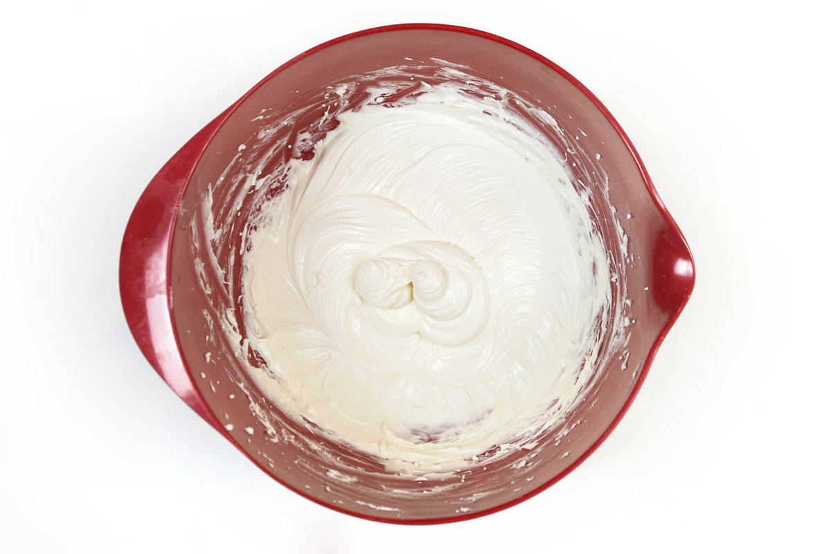 The cream cheese, vanilla extract, powdered sugar, and half of the tub of whipped topping are mixed thoroughly in a mixing bowl.