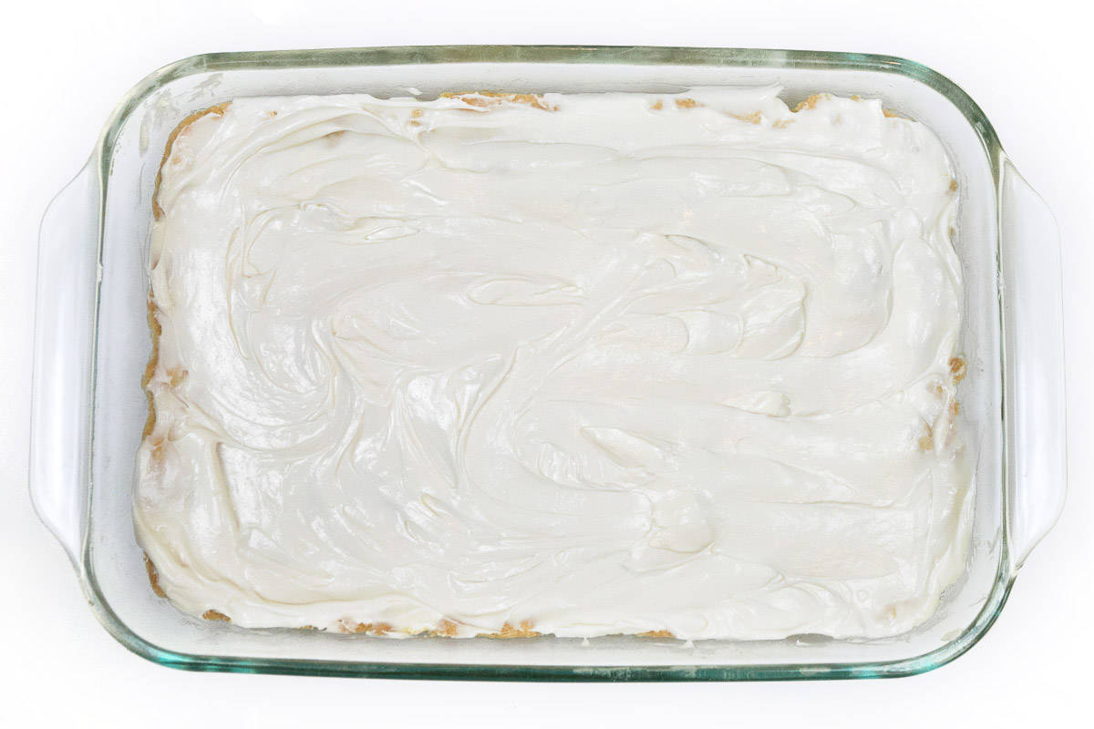 The cream cheese mixture is spread evenly on top of the baked pie crust.