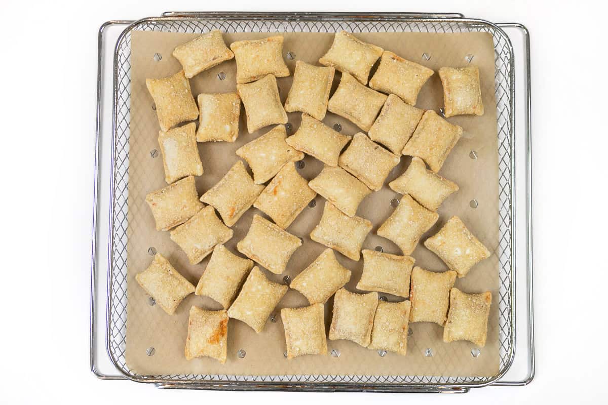 Parchment paper and pizza rolls on the air fryer basket.