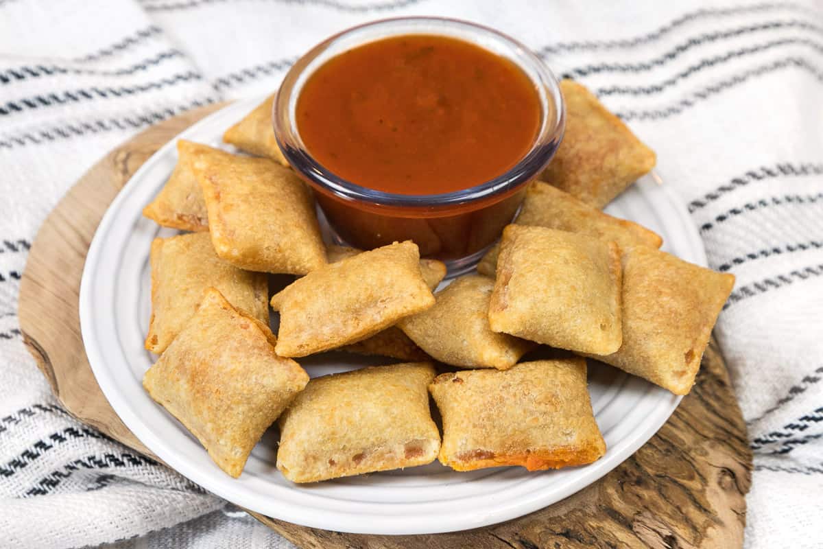 Pizza rolls on a plate with dipping sauce.