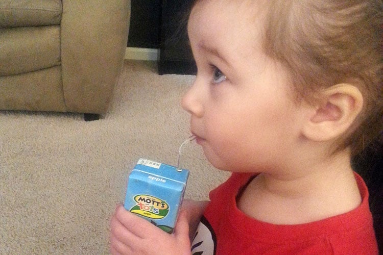 Toddler drinking a juice box.