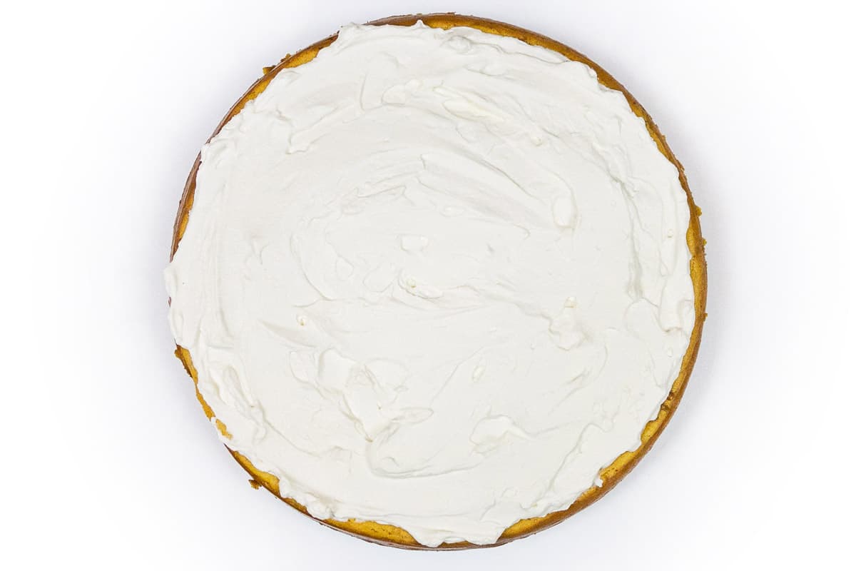 Whipped cream topping spread on the pumpkin cheesecake.