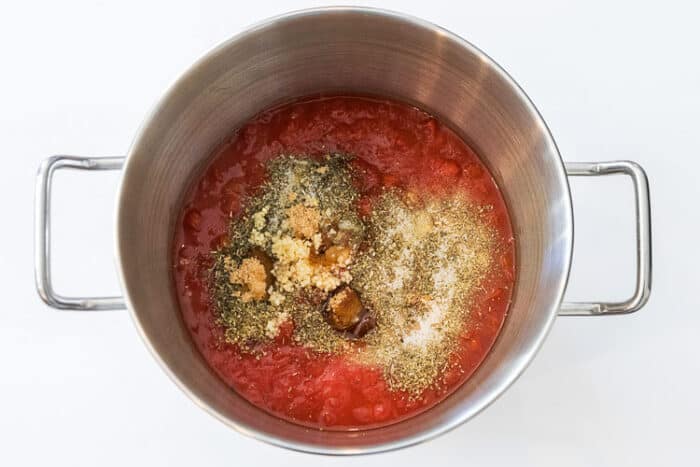 Tomato sauce, tomato paste, diced tomatoes, whole tomatoes, and seasonings in a pot.