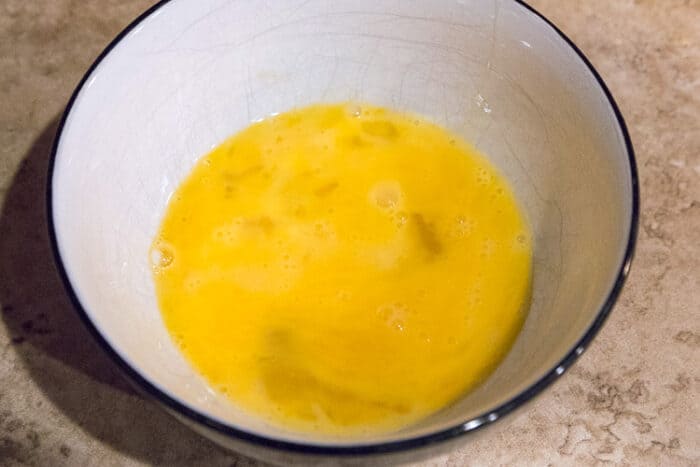 Two beaten eggs in a bowl.
