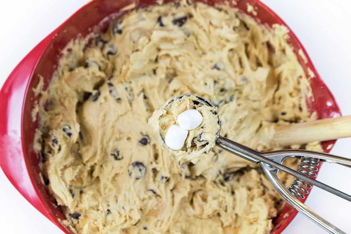 Use a cookie scoop to scoop out the cookie dough. Put mini marshmallows inside the dough.
