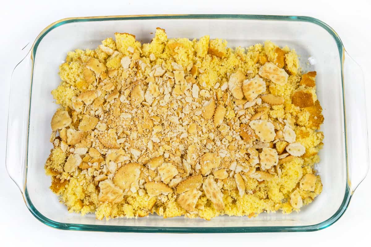 Crumbled Ritz crackers over the top of the crumbled cornbread in a baking dish.