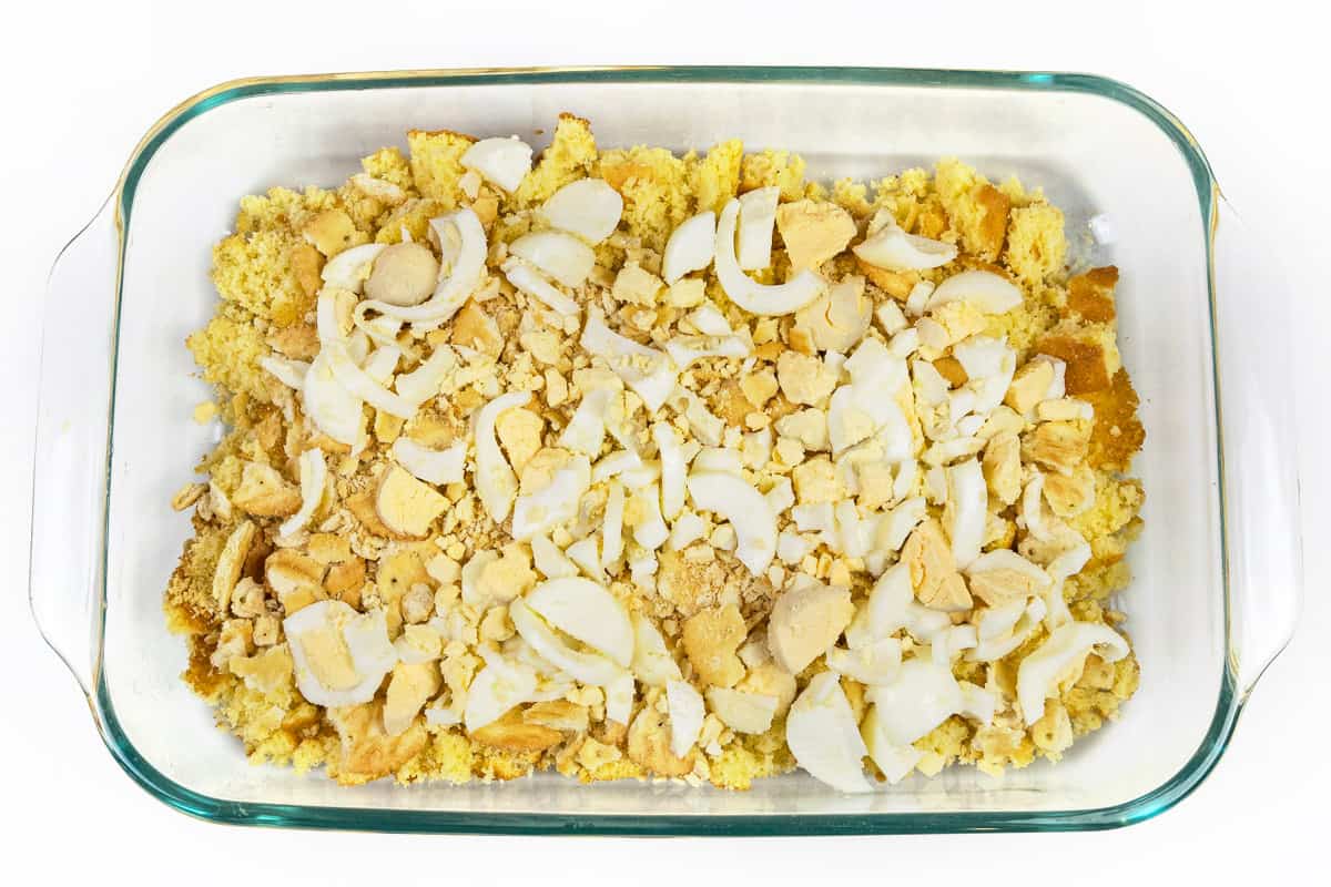 Sliced hard-boiled eggs over the top of the crumbled Ritz crackers and crumbled cornbread in a baking dish.