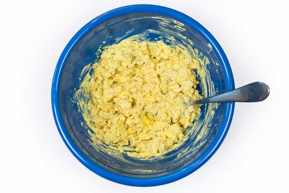 The yellow egg yolks and mayonnaise mixture are thoroughly mixed in a bowl.