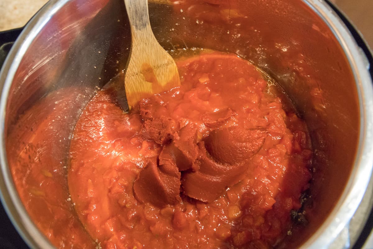 Diced tomatoes, tomato paste, and tomato sauce are added to the ground beef.
