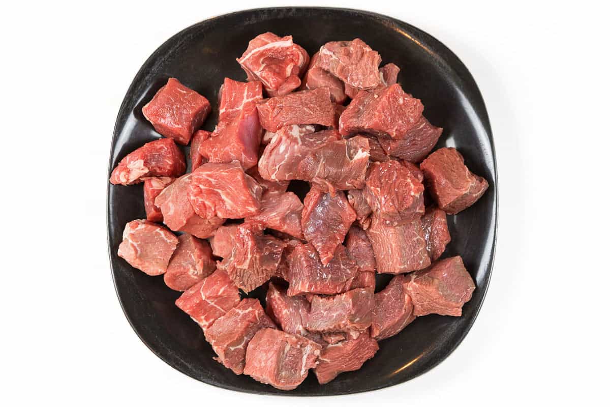 Sirloin steak cut into one-inch cubes on a plate.