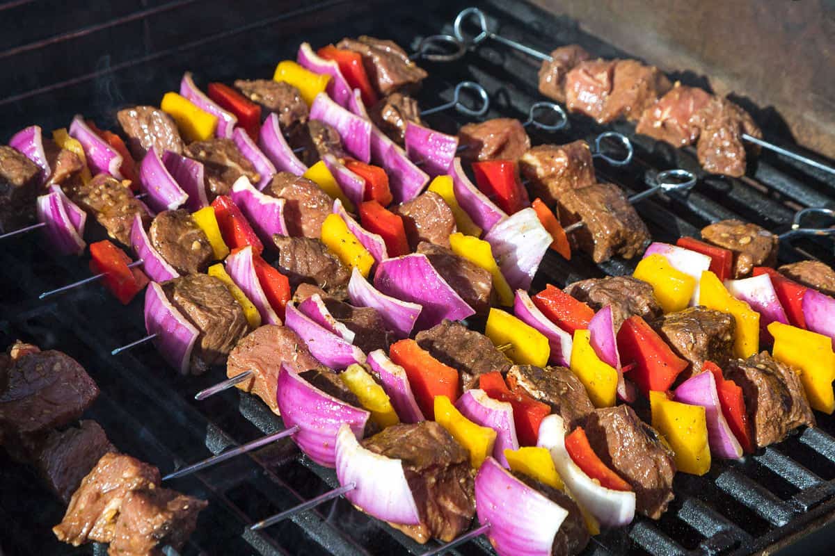The skewers are placed across the grates on the grill.