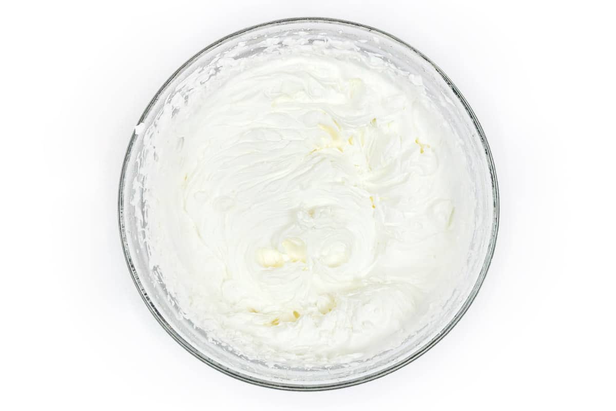 The vanilla extract is added to the whipped cream in the bowl.