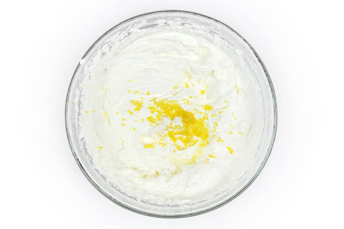 The lemon zest and lemon juice are added to the whipped cream in the bowl.